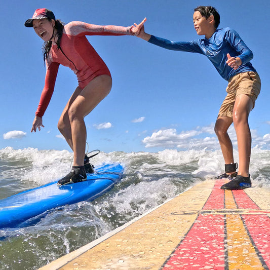 Surf mom wearing surf hat while high fiving son 9