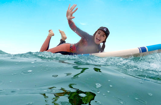 Surfer girl wearing surf hat and waving 2