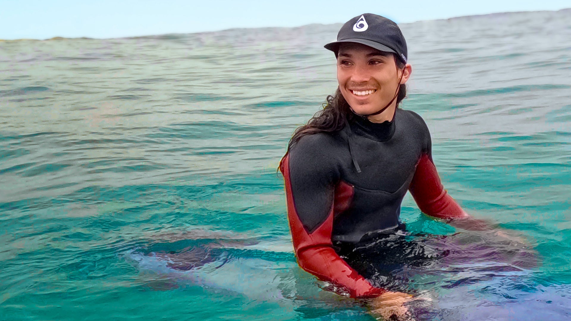 Surfer wearing an eco-friendly surf hat while waiting for waves